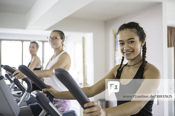 Women exercising on cross trainer in health club