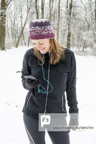 Mid adult woman with knit hat using smart phone in winter