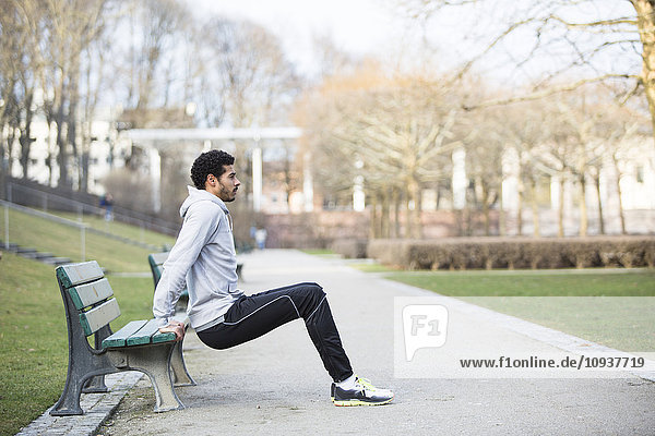 Man in sports clothing doing push-ups on bench