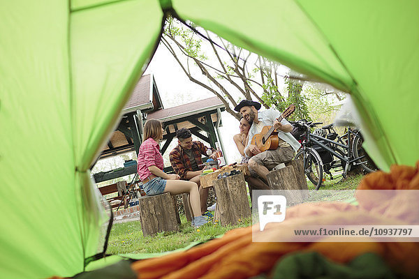 Young man playing guitar at campsite