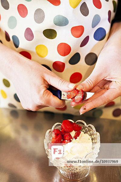 Person die Erdbeeren für die Zubereitung eines Desserts schneidet
