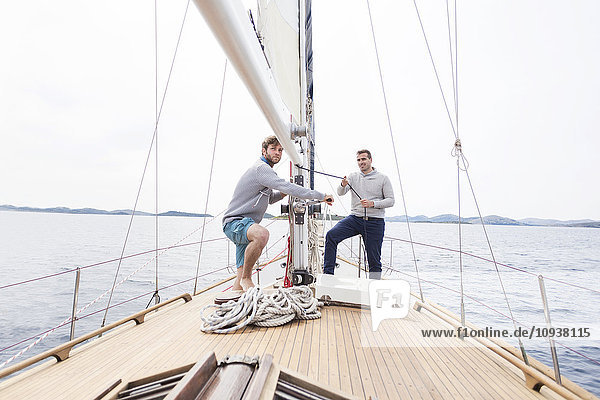 Two men pulling on rope on yacht
