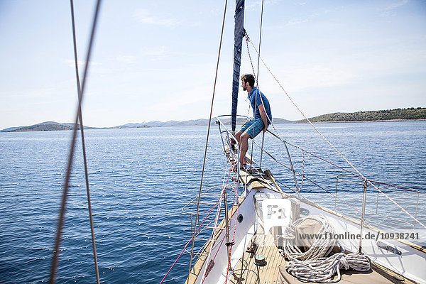 Young man on bow of sailing ship looking out