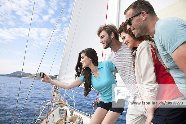 Friends taking self portrait with smartphone on sailboat