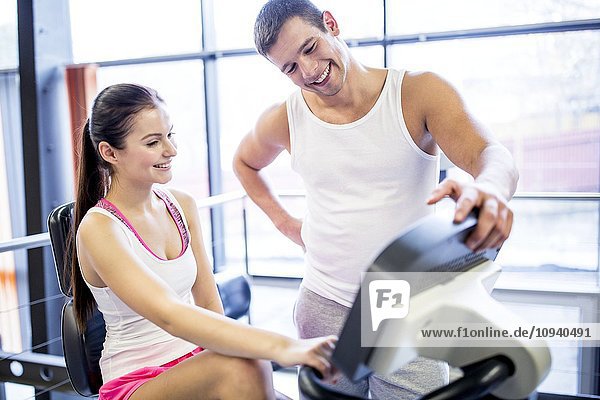 Man instructing woman in gym