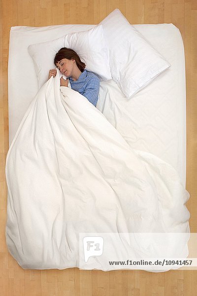 Woman lying in bed holding duvet