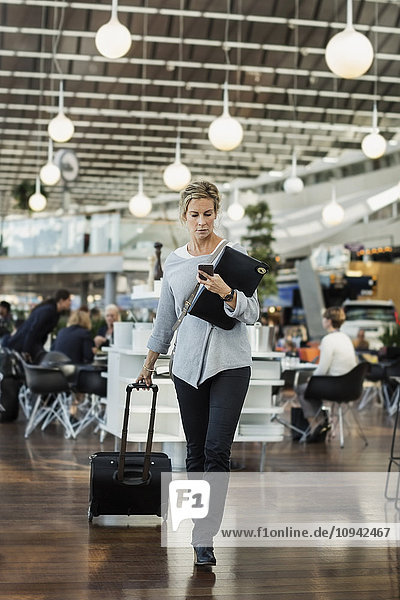 Businessman using smart phone while walking at airport