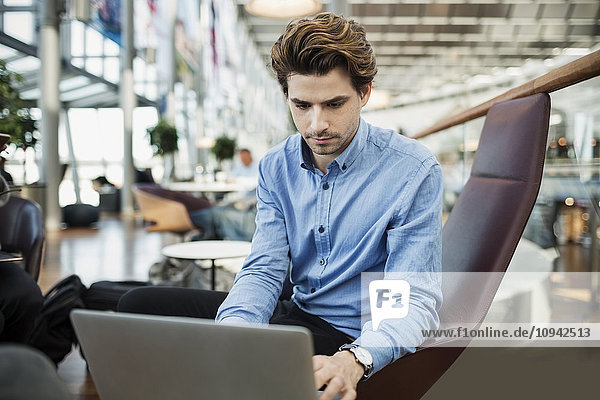 Geschäftsmann mit Laptop in der Flughafen-Lobby