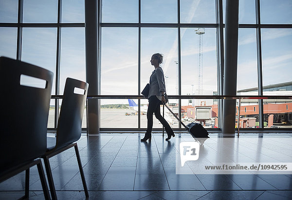 Side view of businesswoman walking with luggage at airport