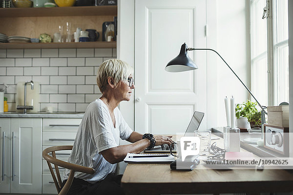 Side view of designer using laptop at home office