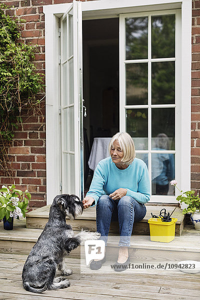 Senior woman sitting with dog at doorway