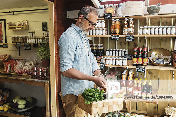 Reifer Mann mit Korb beim Einkaufen im Lebensmittelgeschäft