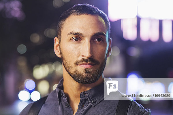 Thoughtful man looking away in city at night