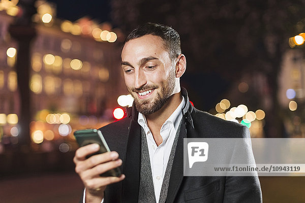Happy man using smart phone in city at night