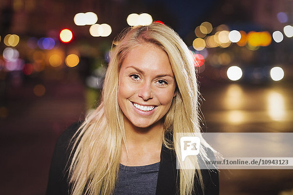 Porträt einer glücklichen jungen Frau auf der Stadtstraße bei Nacht
