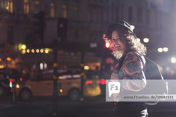 Side view portrait of smiling woman standing on city street at night