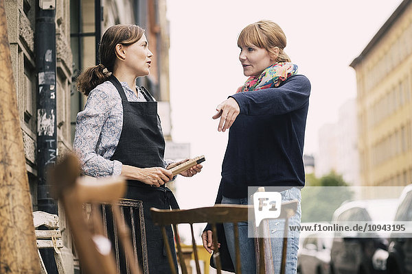 Customer pointing while having communication with owner outside antique shop