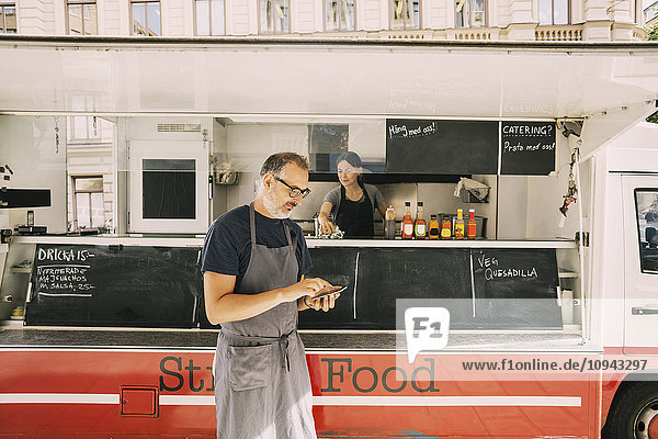Reife Köchin mit dem Handy gegen den Street Food Truck