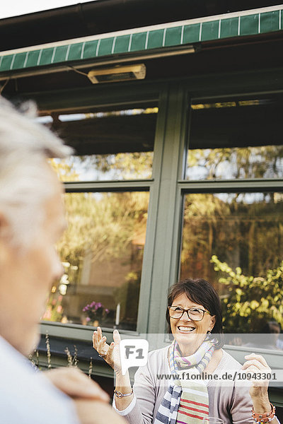 Lächelnde Seniorin mit Gesten im Outdoor-Café