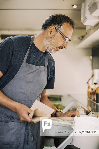 Mature chef working in kitchen of food truck
