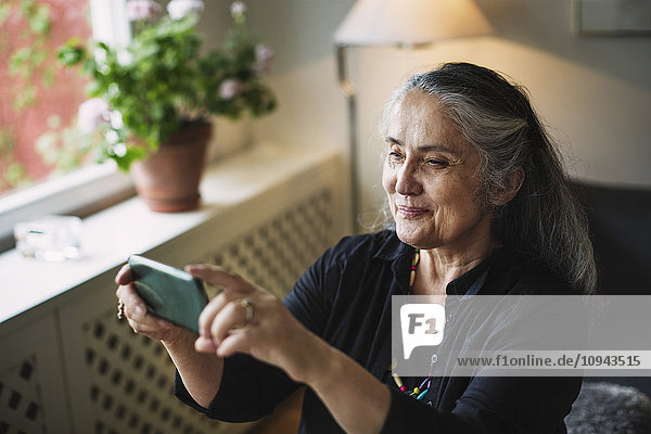 Lächelnde Seniorin beim Fotografieren per Handy
