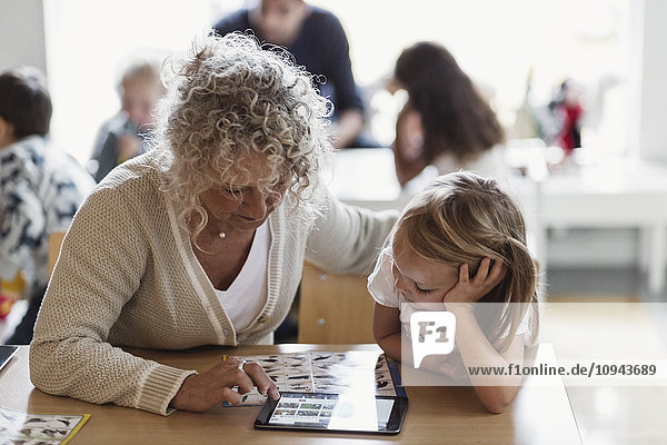 Oberlehrer mit digitalem Tablett und Schüler im Vorschulalter