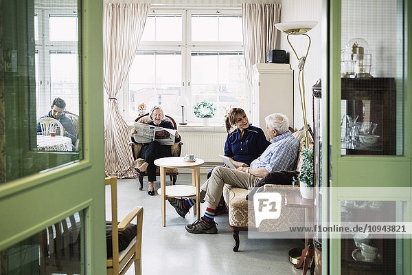 Betreuer mit Seniorenpaar im Wohnzimmer des Pflegeheims