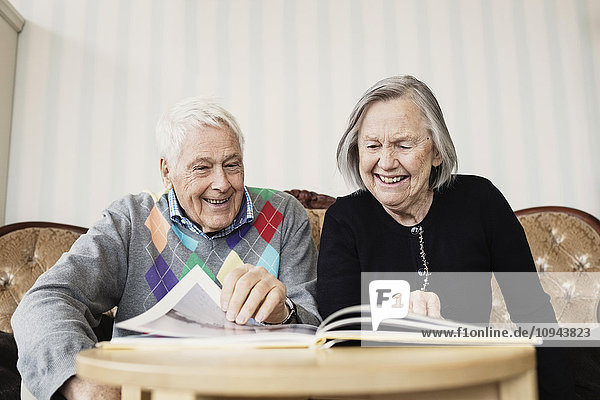 Glückliches Seniorenpaar beim Lesen im Wohnzimmer im Pflegeheim