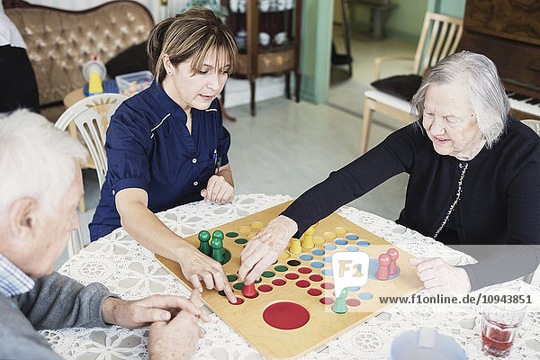 Hausmeister spielt Ludo mit Senioren im Pflegeheim