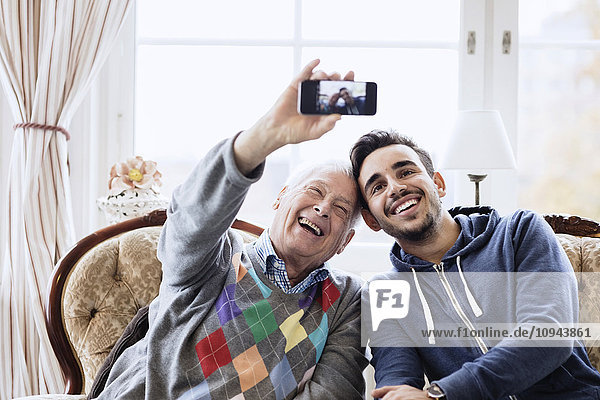 Glücklicher älterer Mann  der Selfie mit Hausmeister durch Smartphone im Pflegeheim nimmt.