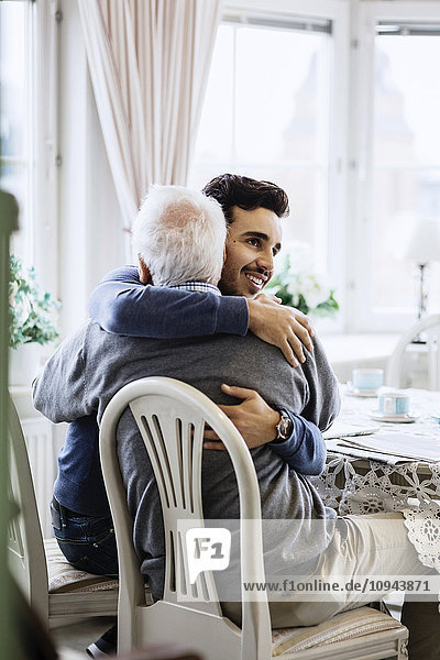 Young caretaker embracing senior male at nursing home