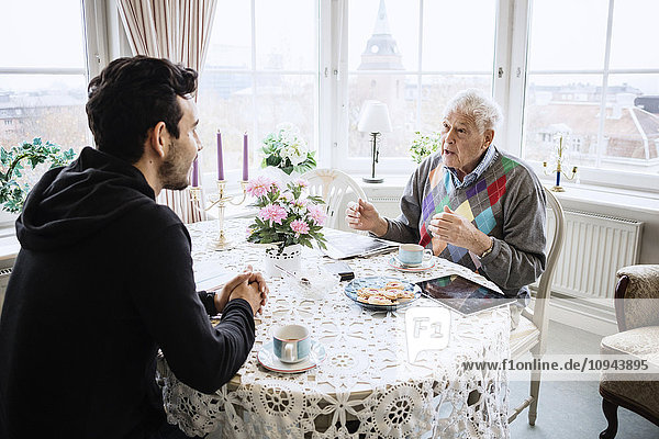 Senior-Mann kommuniziert mit Hausmeister am Esstisch im Pflegeheim