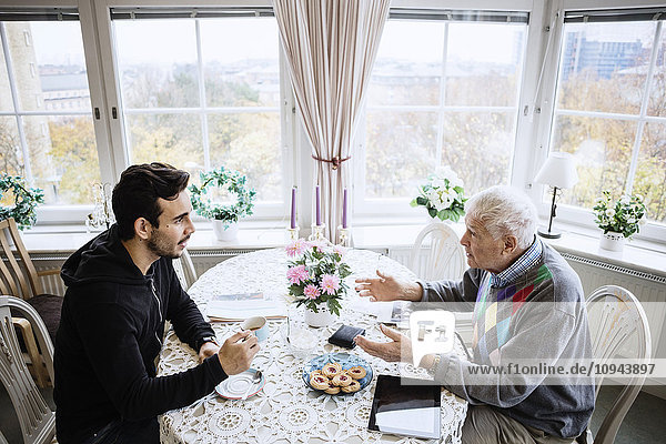 Senior-Mann im Gespräch mit Hausmeister am Esstisch im Pflegeheim