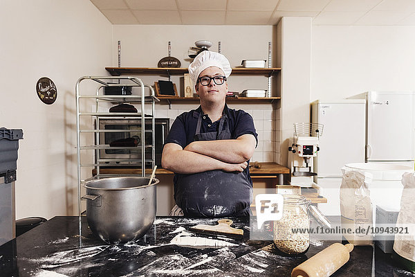Portrait of confident baker standing with arms crossed in commercial kitchen