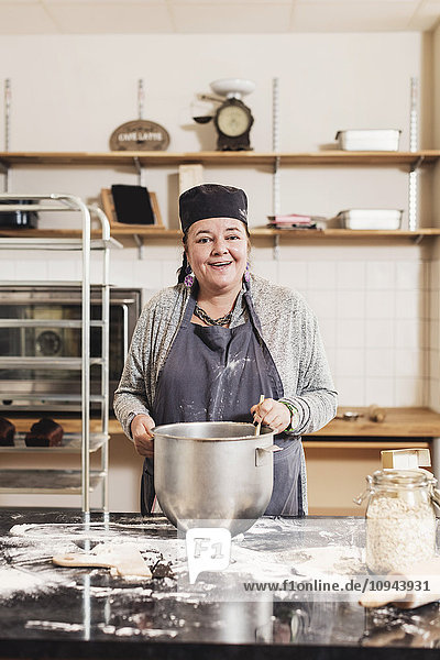 Porträt der lächelnden reifen Bäckerei am Küchenarbeitsplatz