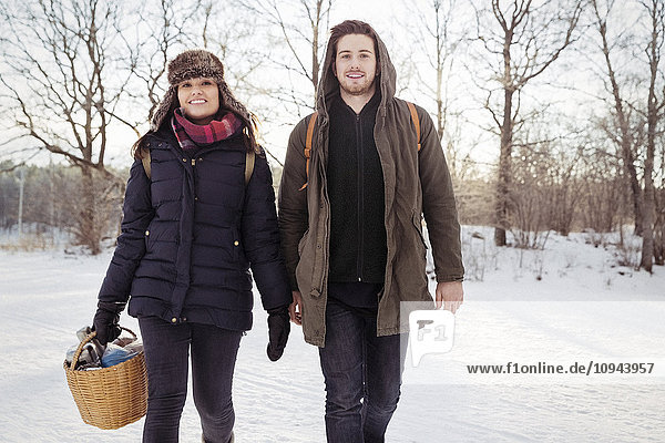 Portrait of smiling couple walking on field during winter