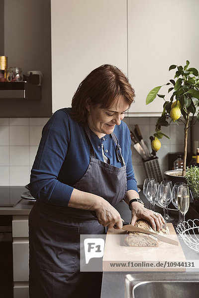 Lächelnde Frau beim Brotschneiden in der Küche