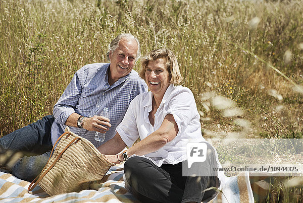 Portrait of happy couple enjoying picnic on grassland
