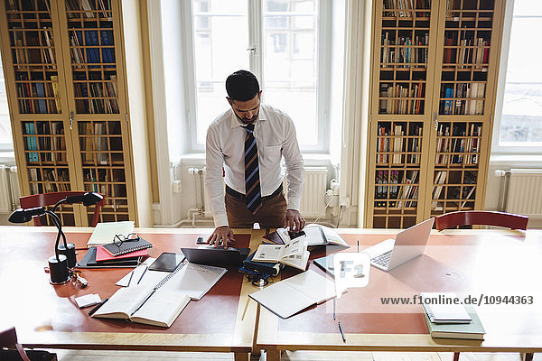 Hohe Blickwinkel auf professionelles Recherchieren im Stehen am Tisch in der juristischen Bibliothek