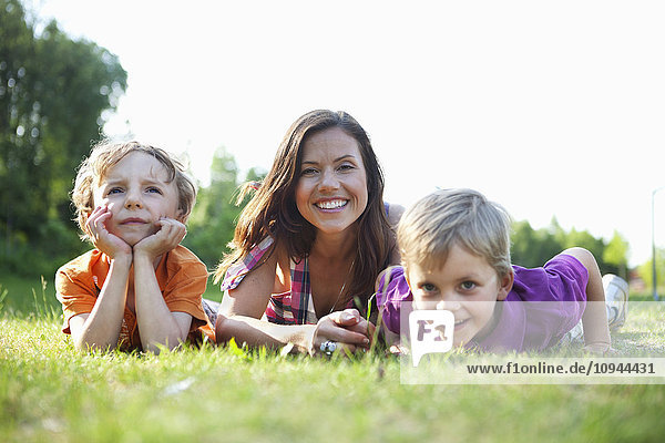 Portrait of a happy mother and children lying on grass