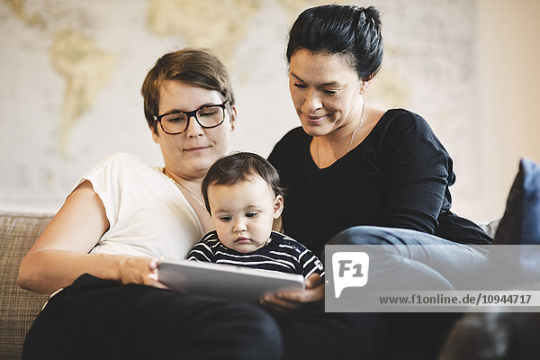 Frauen mit Kleinkind beim Sitzen zu Hause im digitalen Tablett