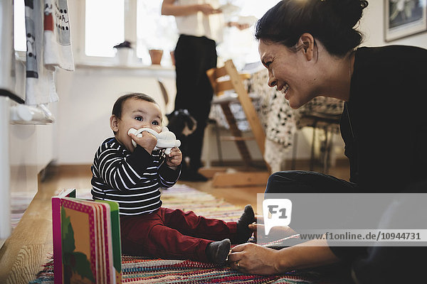 Smiling mother looking at toddler playing with toy