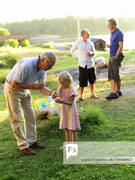 Grandfather talking to girl with men in background