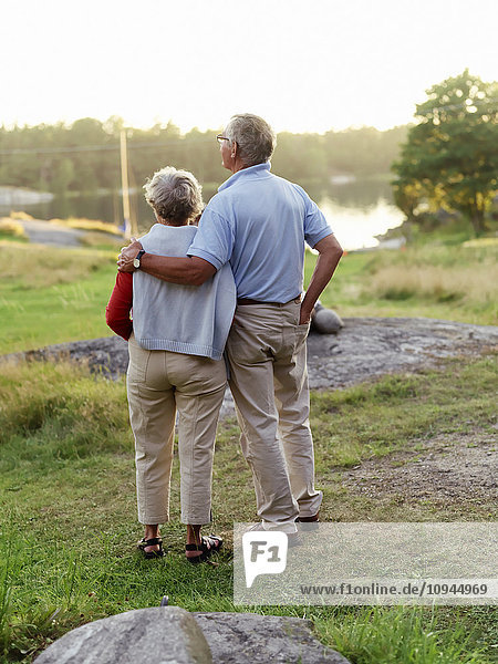 Senior couple standing with arms around