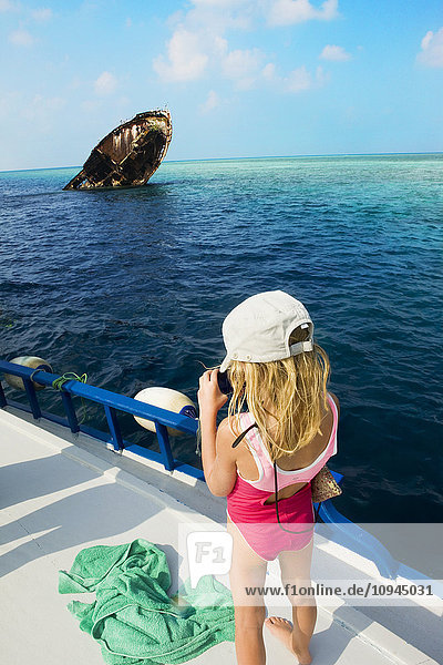Girl photographing on boat near ship wreck