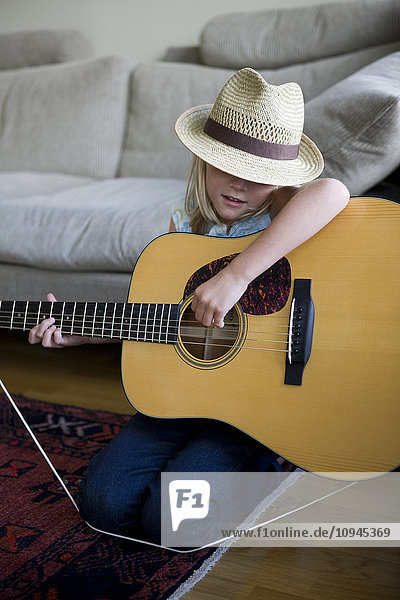 Sweden  Stockholm  girl playing guitar in living room