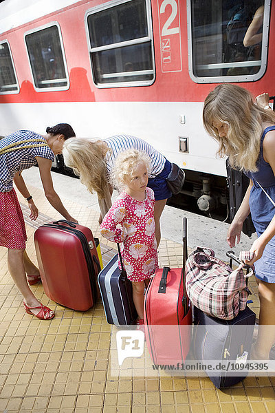 Deutschland  Mutter mit drei Töchtern (4-5 12-13  14-15) und Gepäck am Bahnhof