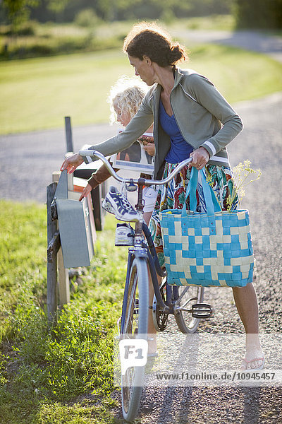 Sweden  mother and daughter (4-5) on bike checking mail