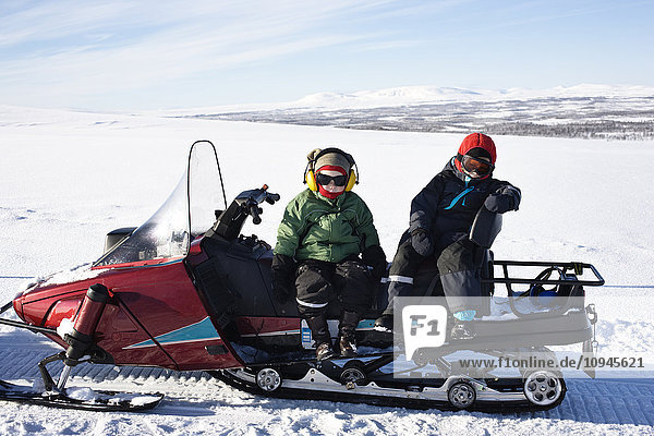 Two boys sitting on snowmobile