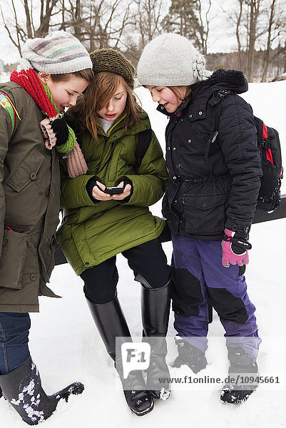 Mädchen mit Mobiltelefon im Schnee